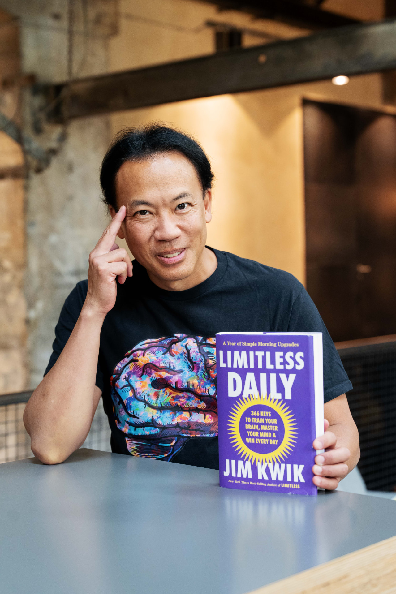 Jim Kwik pointing to his temple beside the Limitless Daily book